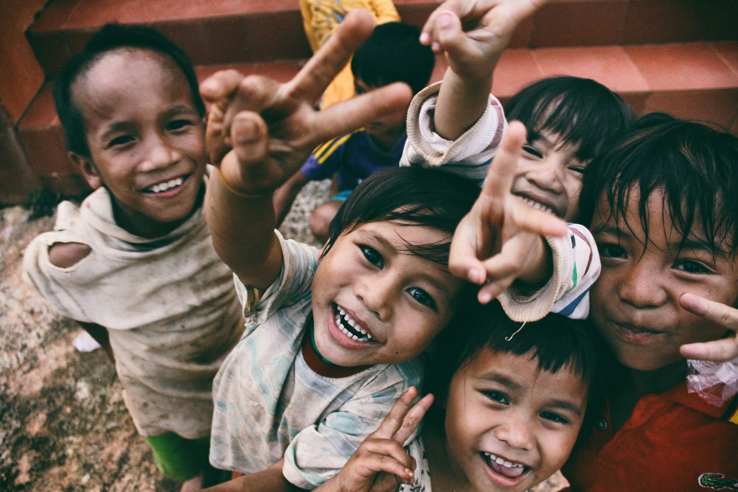 Children in a farming community smiling and reaching toward the camera